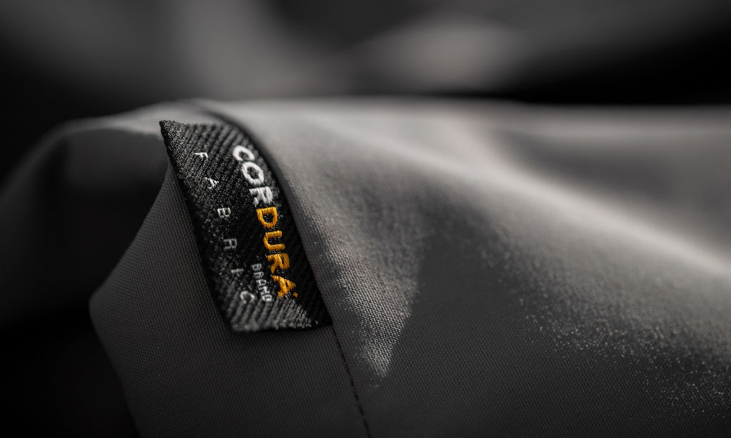 A close-up of the CORDURA Fabric tag attached to gray cloth